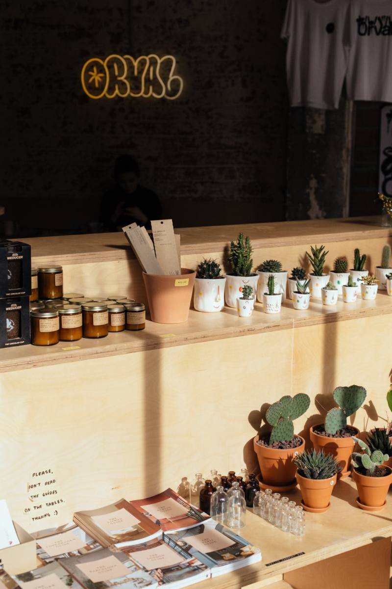 La Cafetería ORVAL tiene una estantería con un montón de cactus, botes de miel y agendas entre otras cosas.