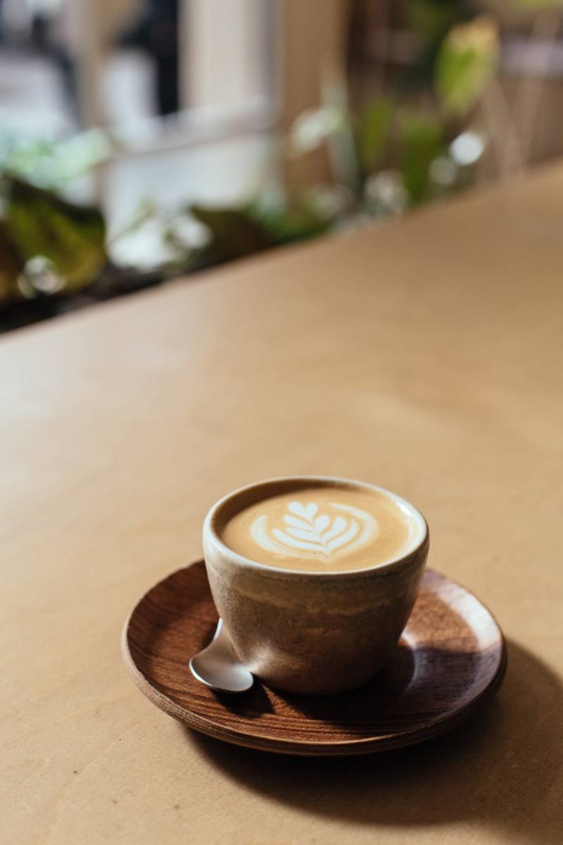 Café cortado decorado con espuma de crema de leche con motivos florales preparado por cafetería Orval.